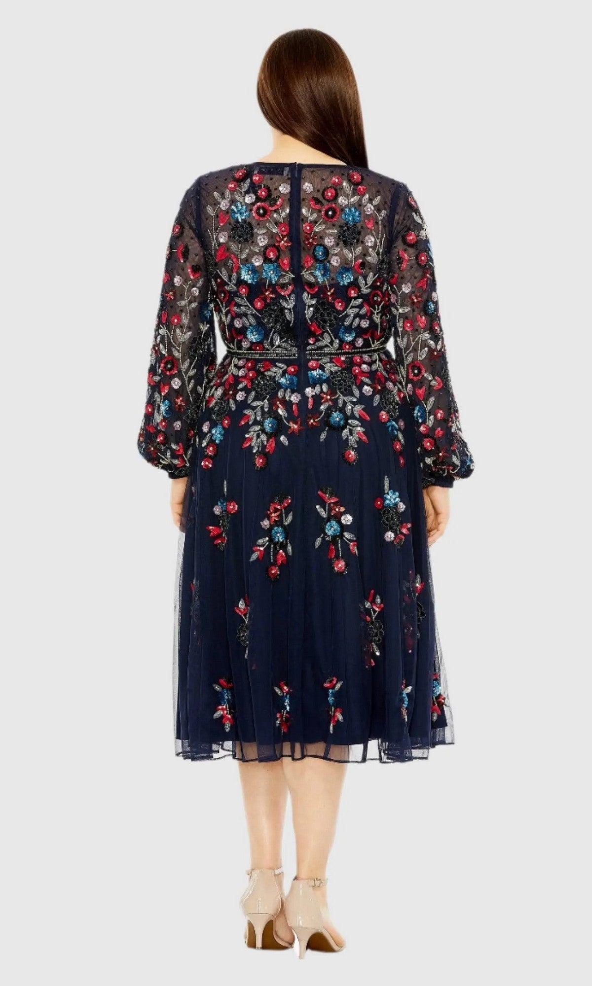 A woman is shown from the back wearing the Mac Duggal 94050, a plus-size cocktail dress in navy blue featuring knee-length hem, colorful floral beadwork, and sheer long sleeves.